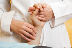 Doctor with one hand in the patient's hand and the other hand on the patient's wrist